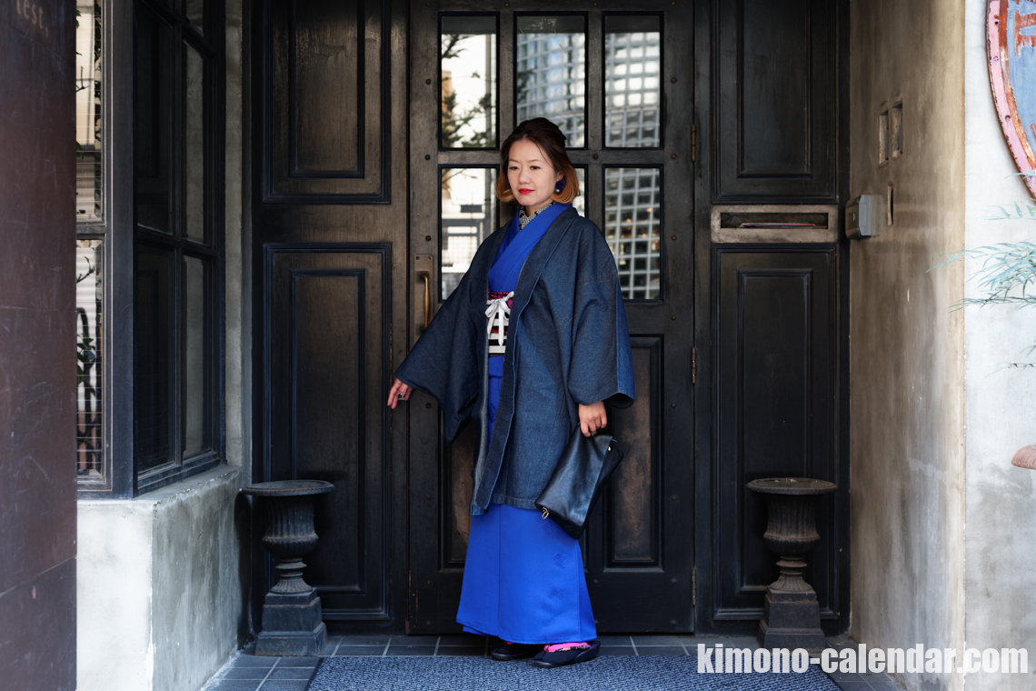 青い色無地の着物にデニムの羽織を羽織っている女性